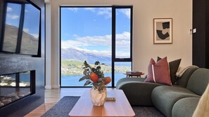 A modern living room with a large window, a sofa, a coffee table, and a vase with flowers.
