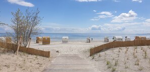 A beach with wooden walkways leading to numbered beach huts.