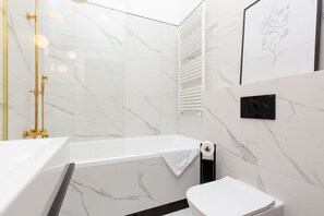 Une salle de bain moderne équipée d’une baignoire, de toilettes et d’un espace douche.