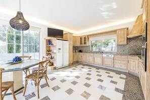 A modern kitchen with wooden cabinets, a granite countertop, and a dining area with a glass table and wicker chairs.