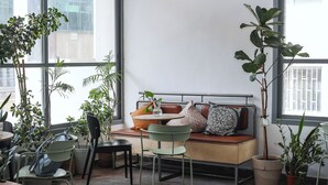 A cozy seating area with a cushioned bench, a small table, and several potted plants. - Domus Metro Hotel (Tel Aviv)