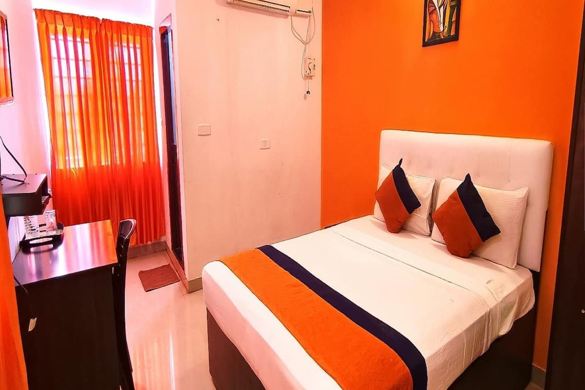 A hotel room with a bed, a desk, and a chair.