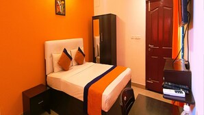 Una habitación de hotel con una cama, un armario, un escritorio con una computadora y una puerta.