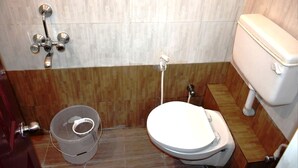 Un baño con inodoro, ducha y un cubo.