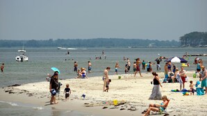 Uma praia cheia de gente, barcos e guarda-sóis.