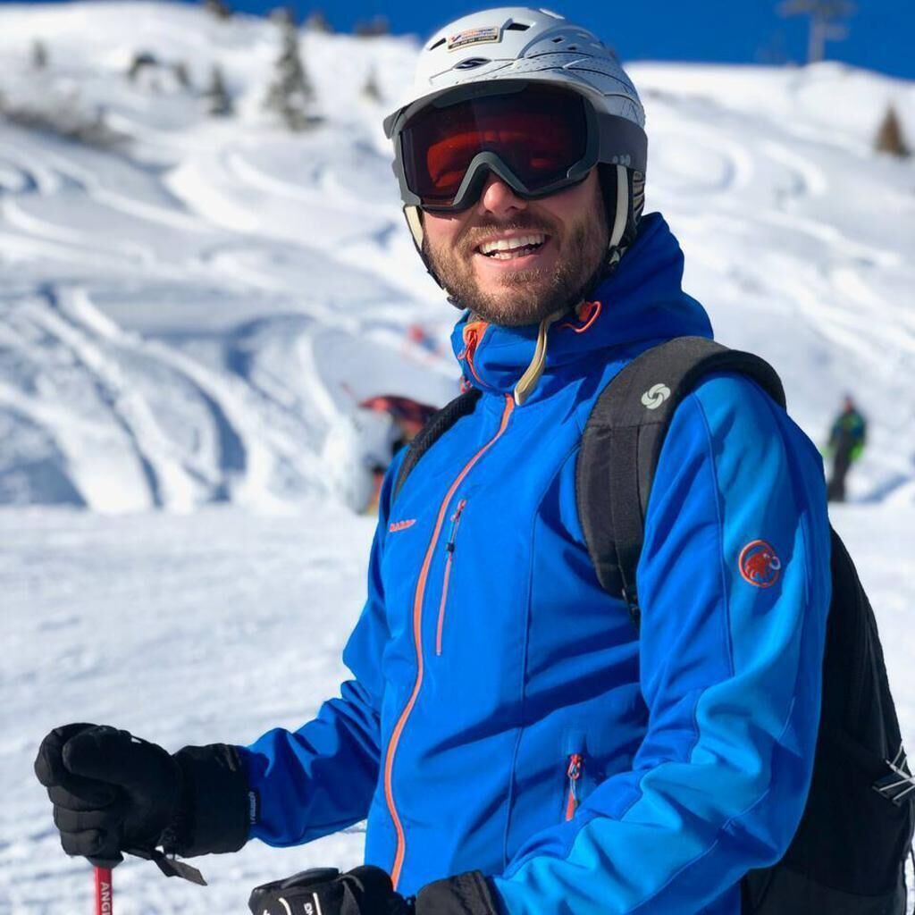 Una persona con chaqueta azul y casco en una ladera nevada.