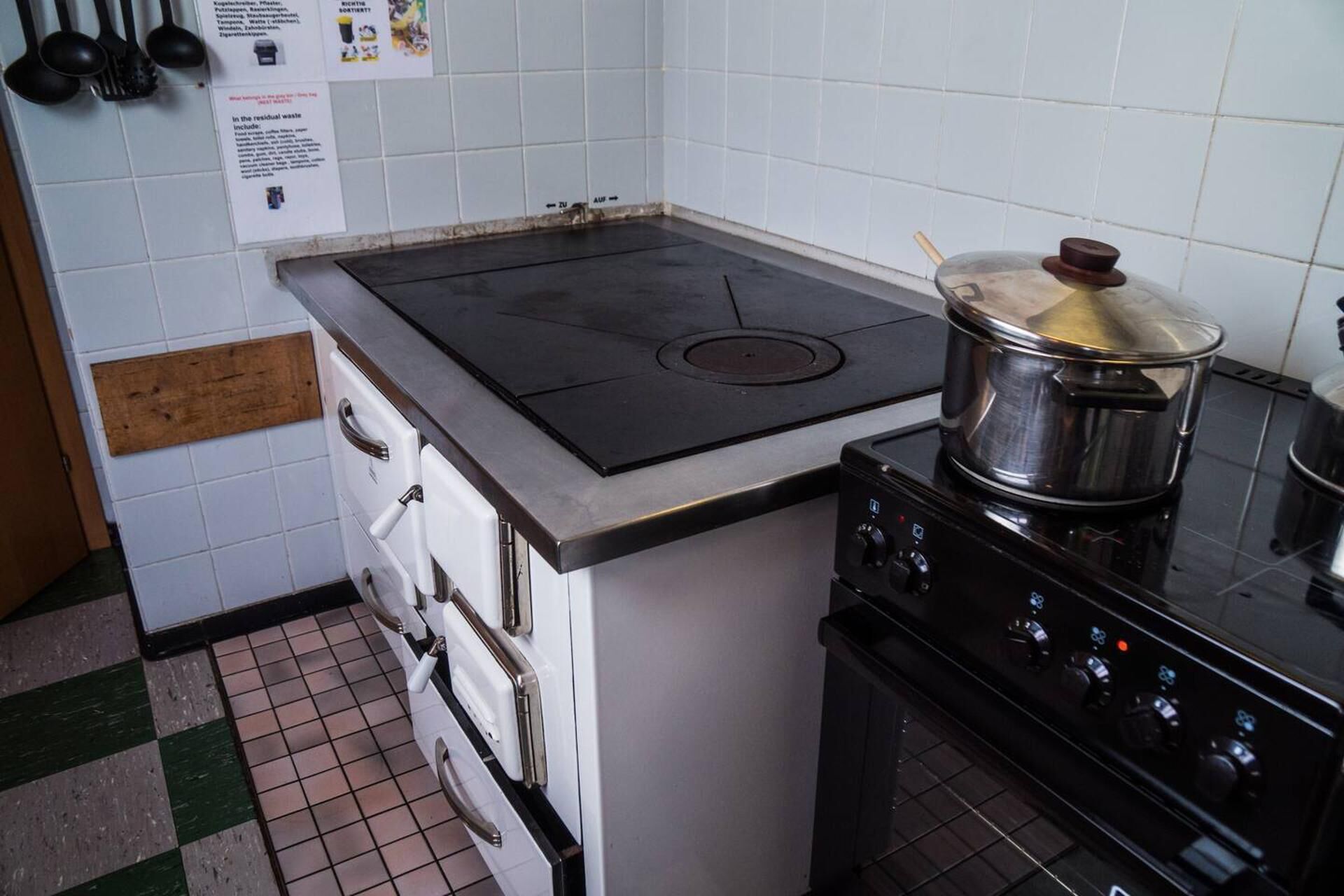 A kitchen with a stove, oven, and a pot on the stove. There are cabinets and a tiled backsplash.