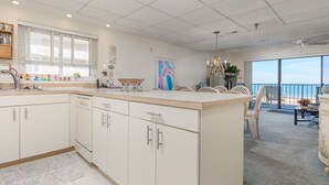 A modern kitchen with white cabinetry, a large island, and a view of the ocean.