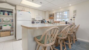 A modern kitchen with a central island, bar stools, and built-in appliances.