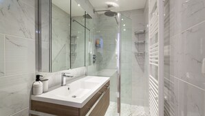 A modern bathroom with a glass-enclosed shower, a large mirror, and a wooden vanity with a white sink. - Les Studios de la faisanderie 1 (Chantilly)