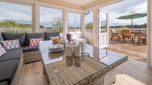 Ein geräumiger Balkon mit einem Glastisch, Korbmöbeln und Blick auf die Landschaft.