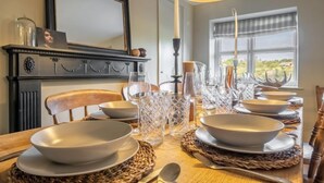 Een eettafel gedekt met kommen, glazen en bestek, met een spiegel en decoratieve items aan de muur.