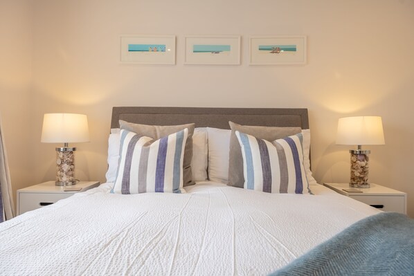 A neatly made bed with striped pillows, two bedside lamps, and three framed pictures on the wall. - The Hideaway (D), Docking, Norfolk (Docking)