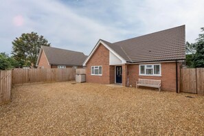 A two-story brick house with a tiled roof, a fenced backyard, and a bench. - The Hideaway (D), Docking, Norfolk (Docking)