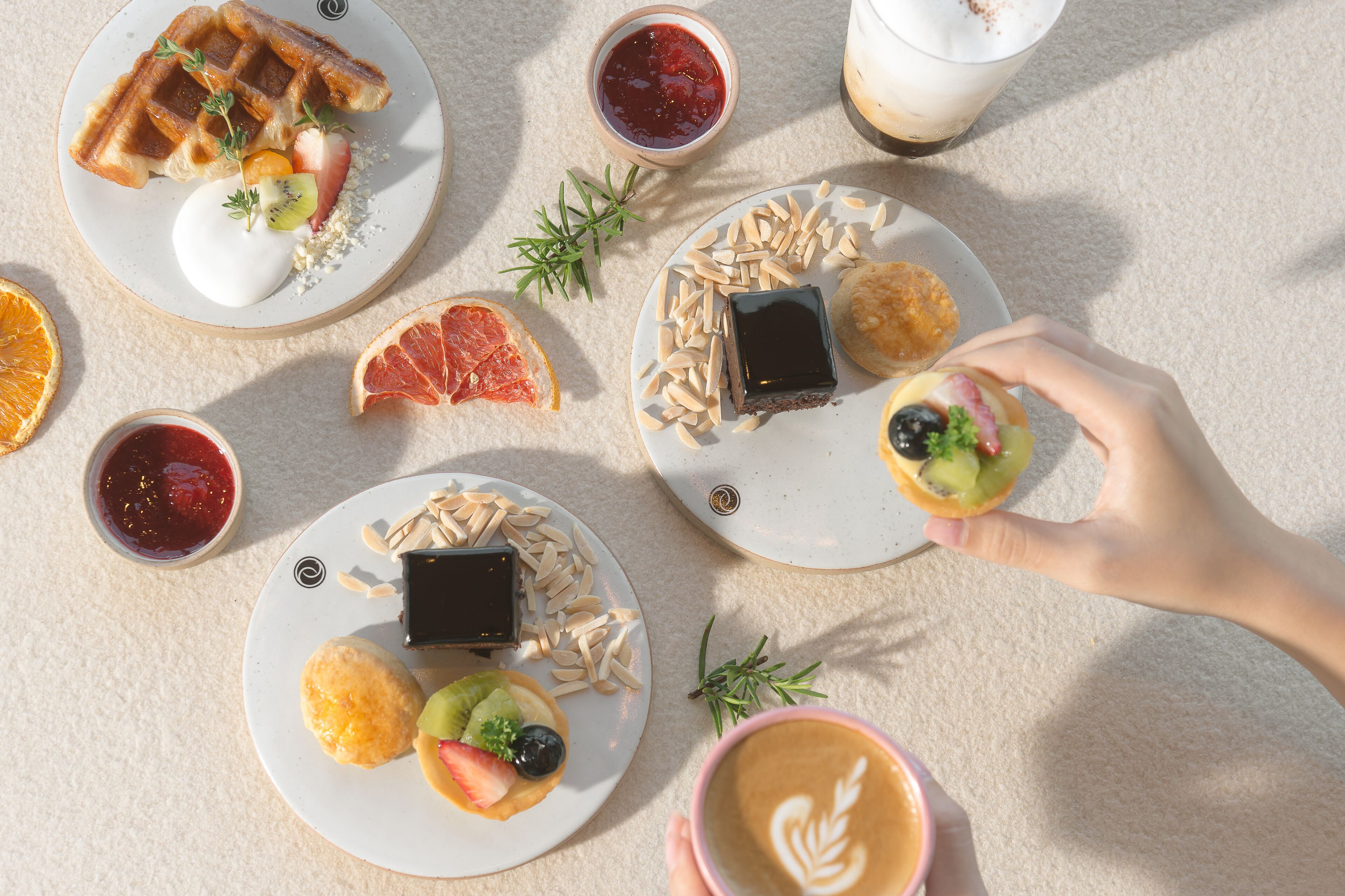 A table with various breakfast items including waffles, pastries, and coffee.