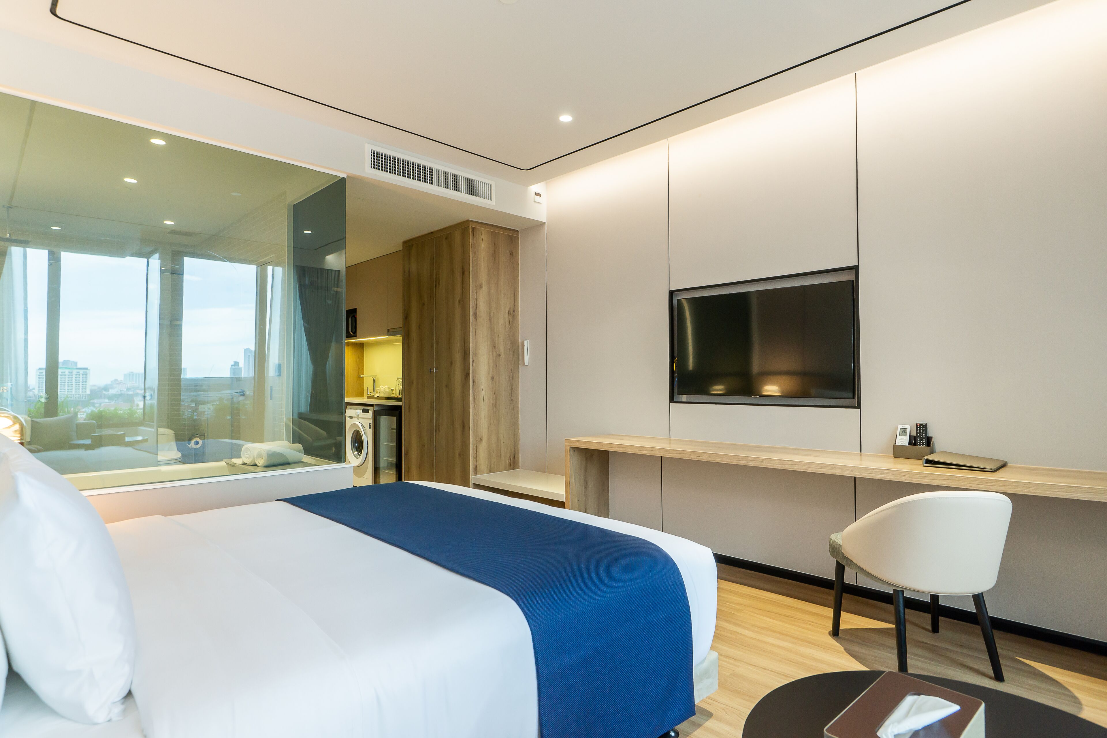 Een moderne hotelkamer met een groot bed, een bureau, een televisie en uitzicht op de stad.