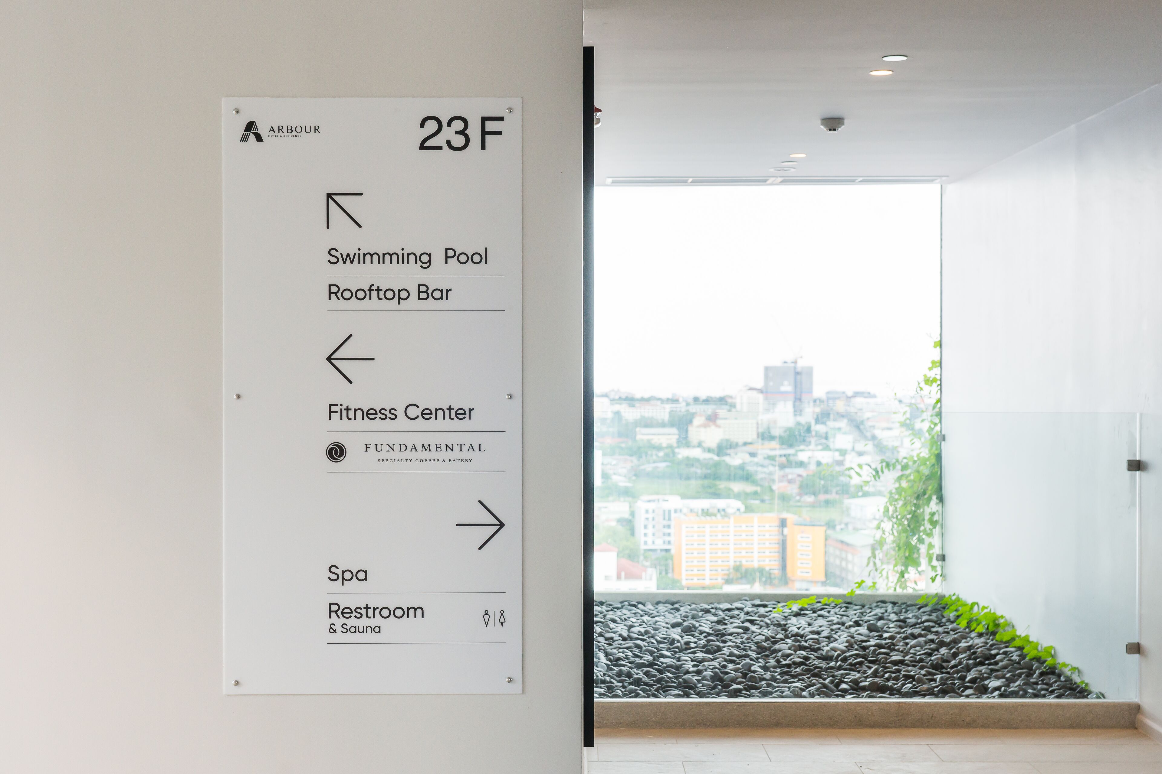 Ein Hotelschild mit Wegweiser zu Annehmlichkeiten wie Schwimmbad, Dachterrasse-Bar, Fitnesscenter, Spa und Toilette.