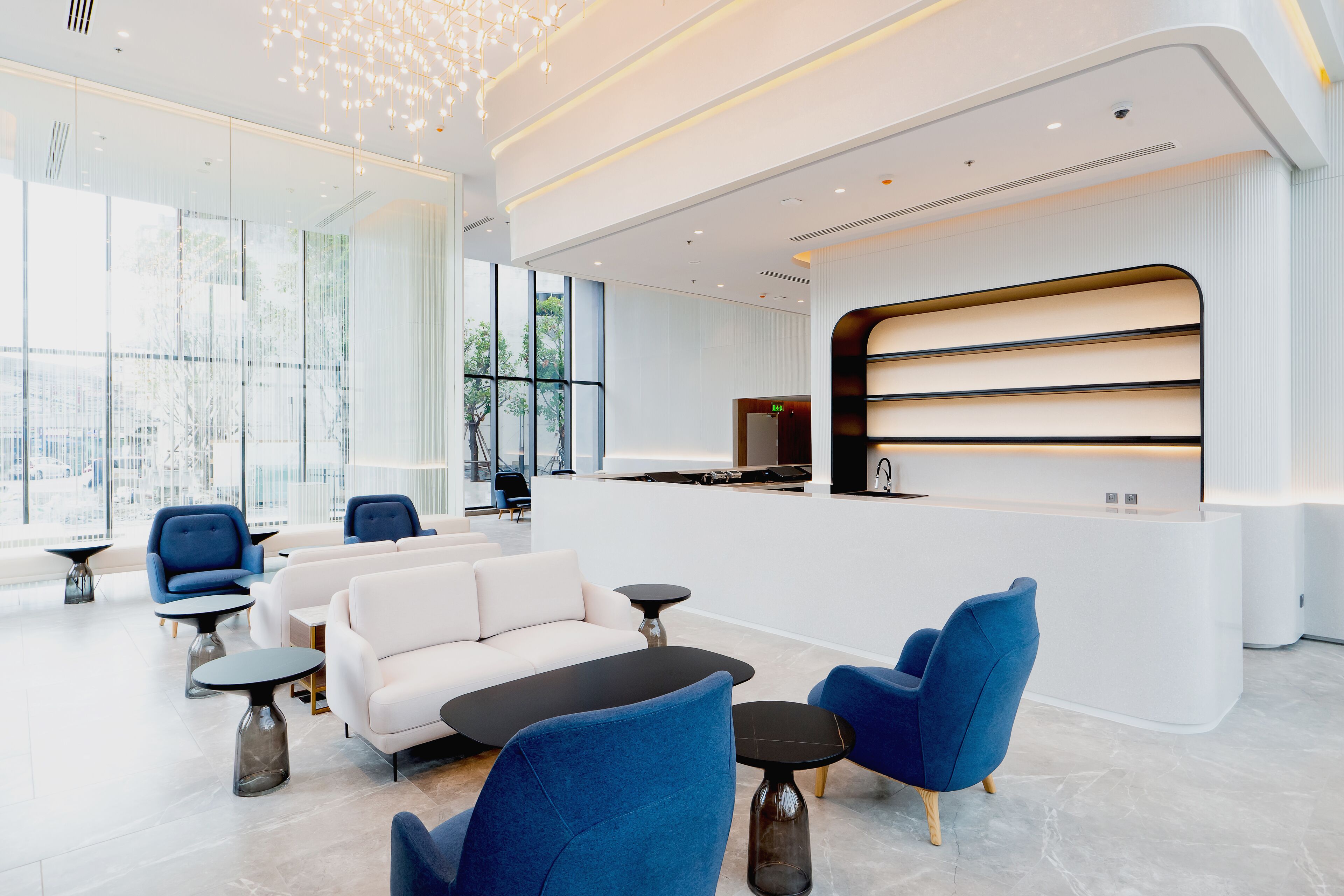 A modern lobby with a reception desk, seating area with sofas and chairs, and large windows offering views.
