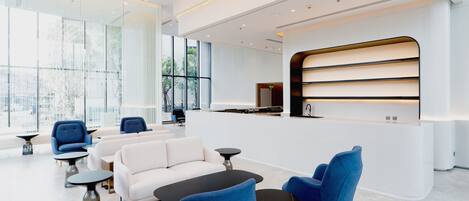 A modern lobby with a reception desk, seating area with sofas and chairs, and large windows offering views.