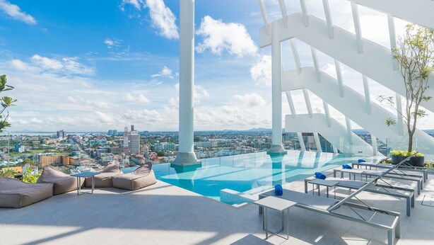 An infinity pool with a city view, lounge chairs, and a modern architectural design. - Arbour Hotel And Residence Pattaya (Pattaya)