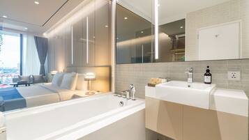 A modern bathroom with a large bathtub, a vanity with a sink, and a mirror.