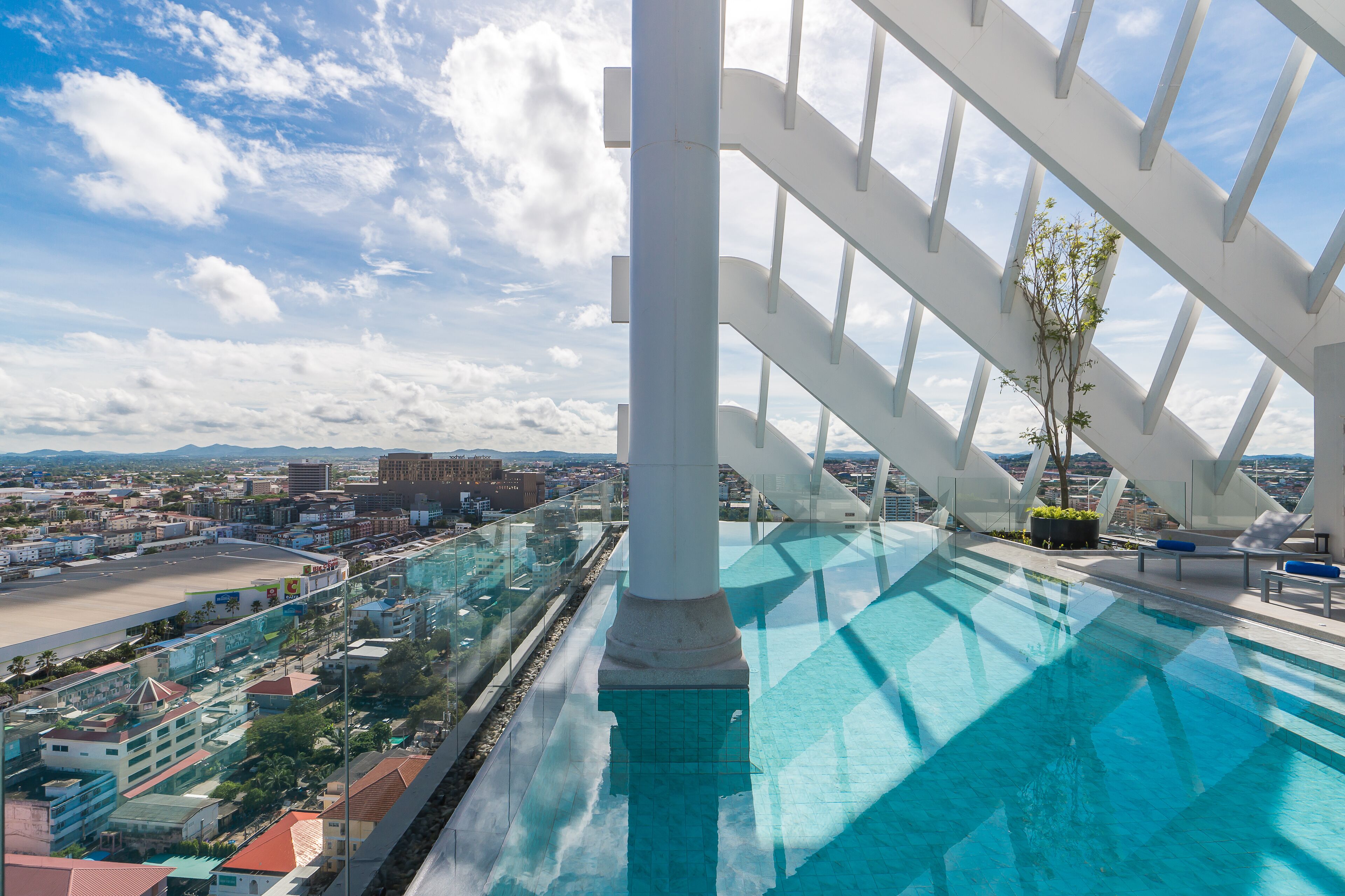 Une piscine sur le toit offrant une vue dégagée sur le paysage urbain, un design architectural moderne et un espace détente agrémenté de plantes.