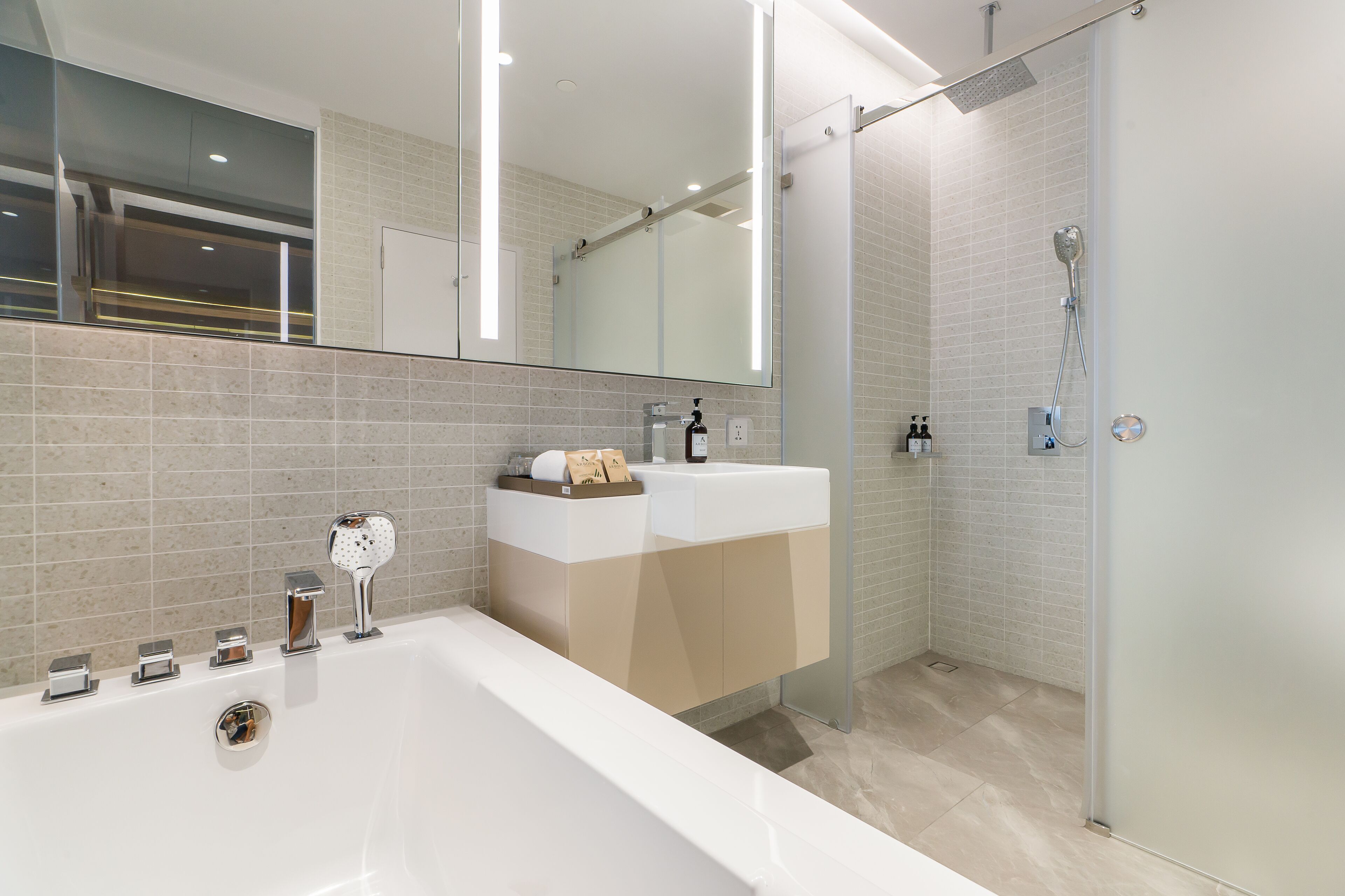 Une salle de bain moderne dotée d’une grande baignoire, d’une douche à parois de verre et d’un meuble-lavabo avec un miroir.
