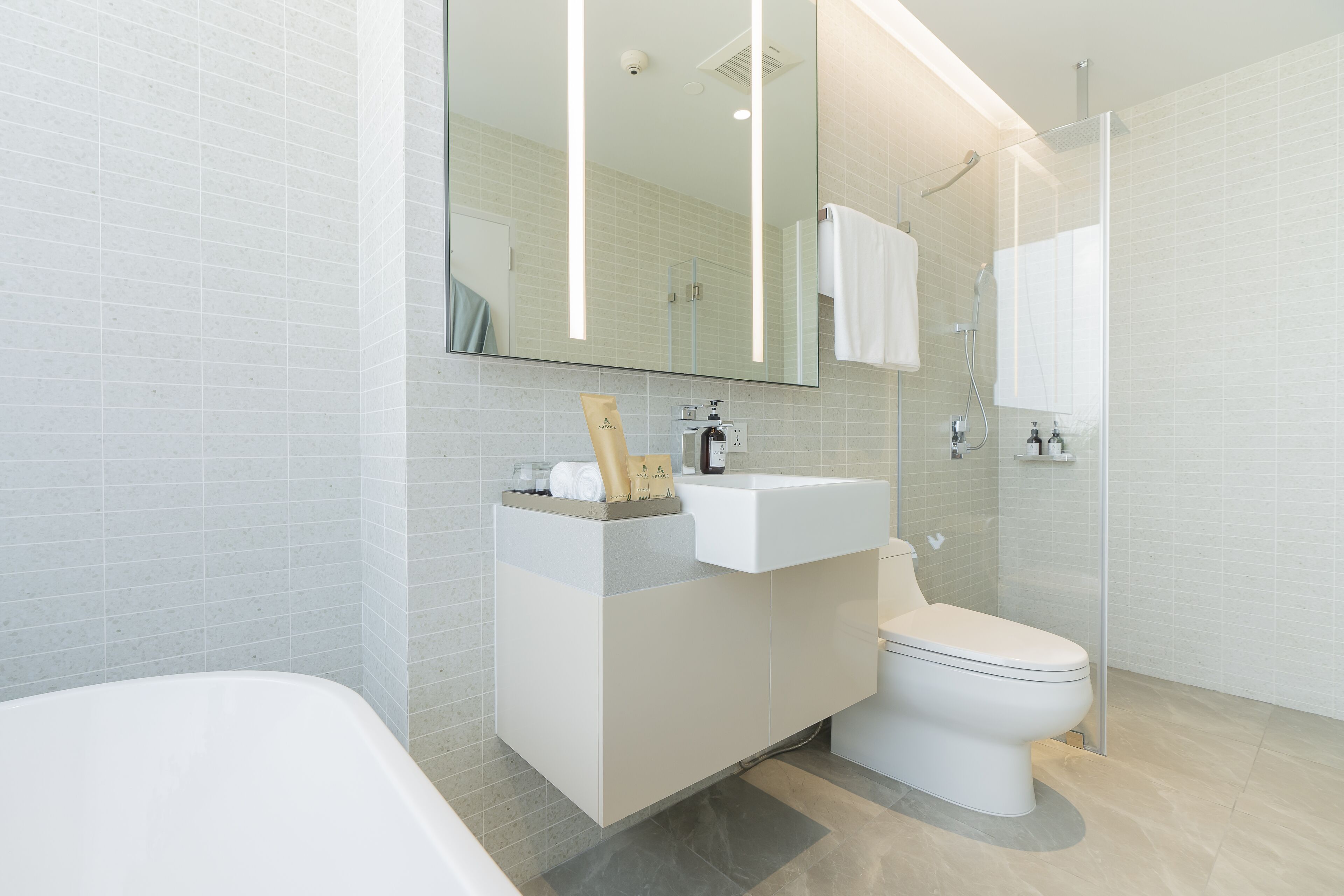 Ein modernes Badezimmer mit Badewanne, Toilette, Waschbecken und einer Duschkabine aus Glas.