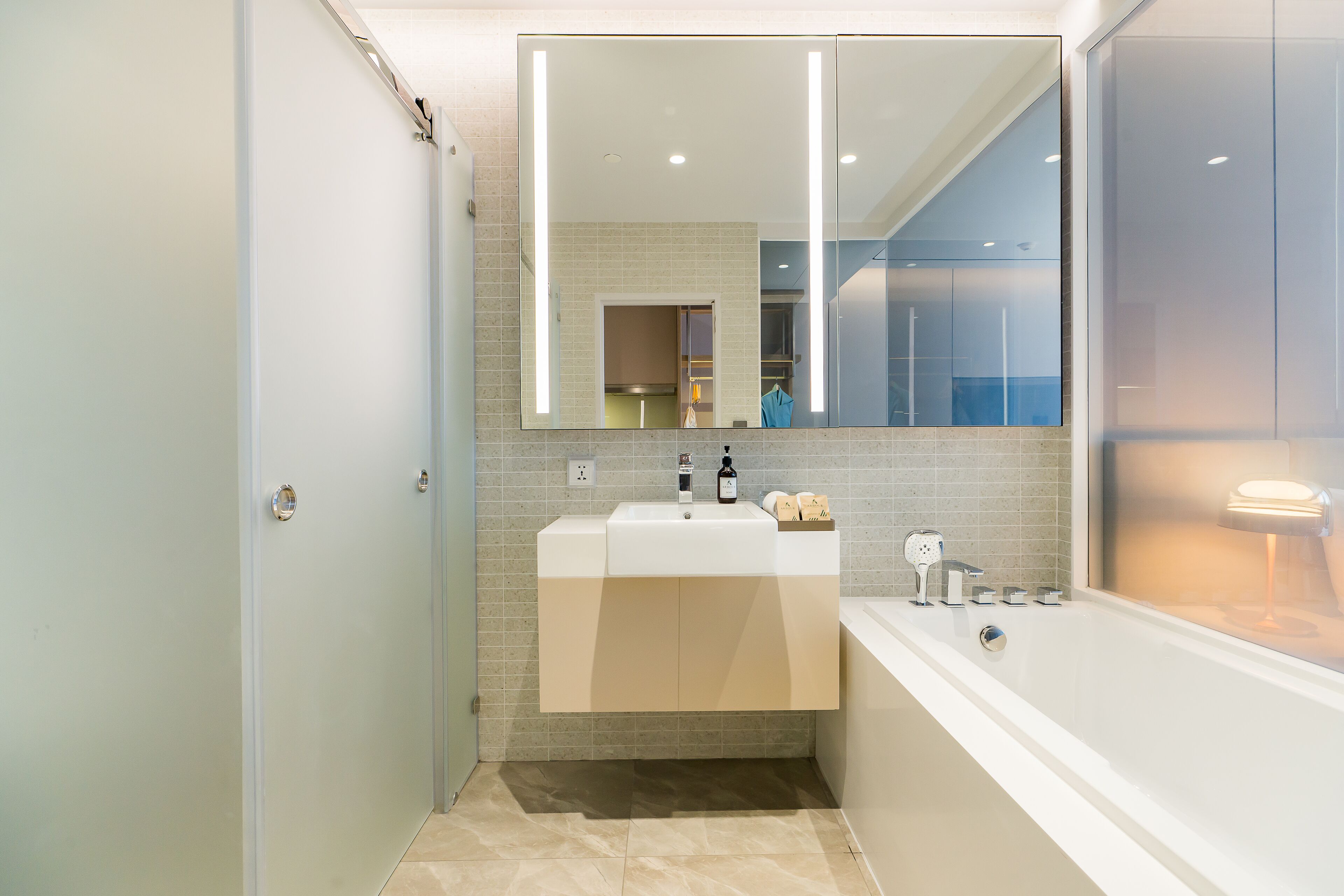 Une salle de bain moderne avec un grand miroir, un lavabo et une baignoire.