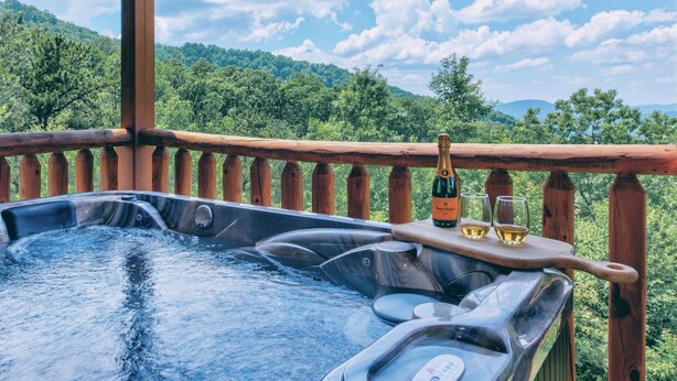 A hot tub with a wooden deck and a scenic view of a forested hill. - Whiskey Mountain Lodge * Mountain View!! *Private Mountain Setting *Hot Tub *Pool Table *Ping Pong (Sevierville)