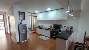 Een moderne keuken met witte kasten, een zwart aanrecht en een roestvrijstalen koelkast.