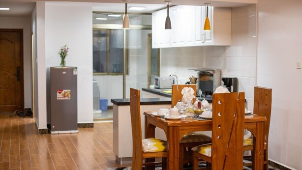 Een kleine keuken met een eettafel, stoelen en een koelkast.