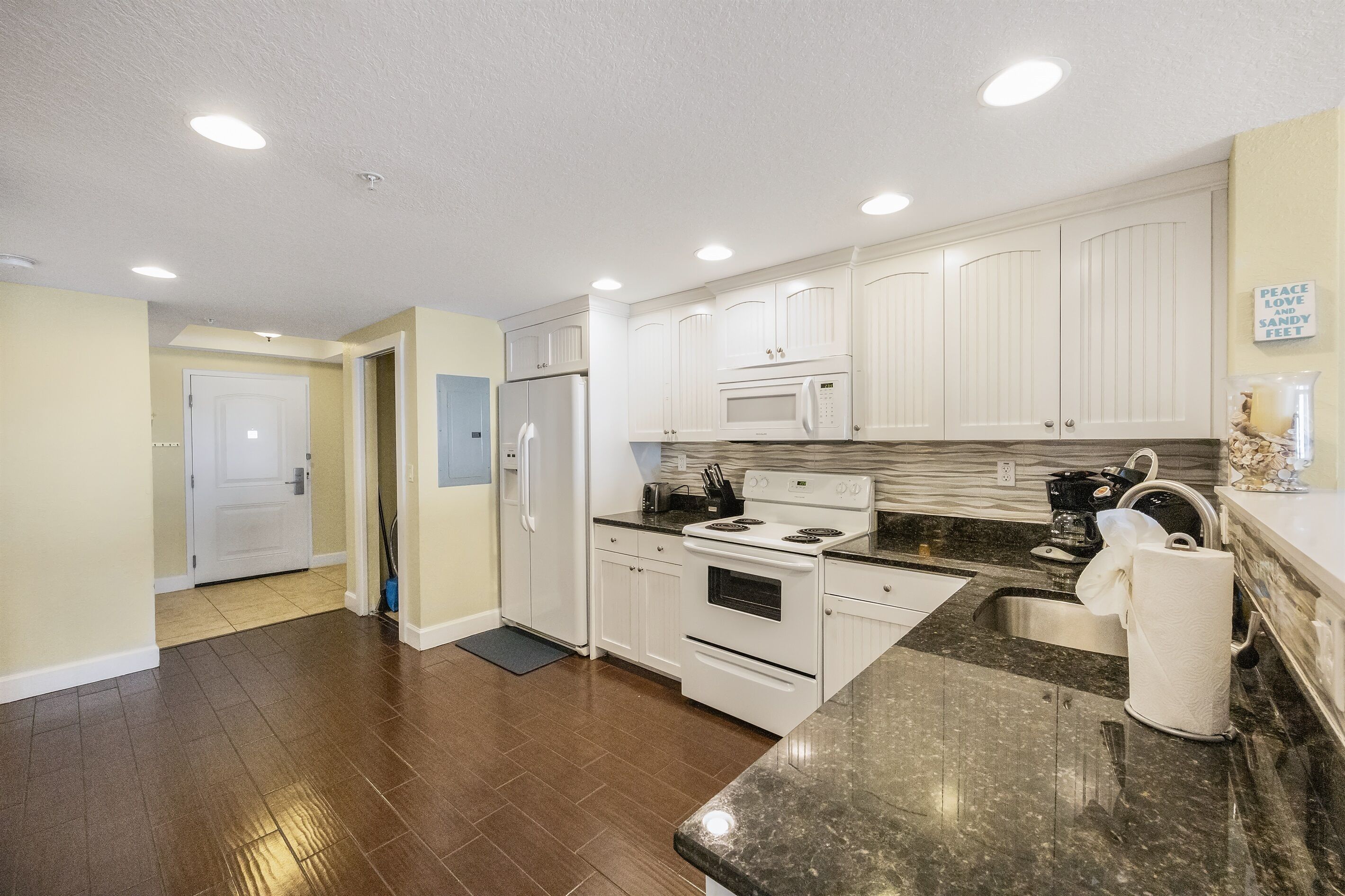 A modern kitchen with white cabinets, a stainless steel sink, and a granite countertop.