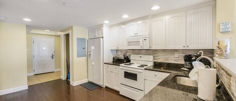 A modern kitchen with white cabinets, a stainless steel sink, and a granite countertop.