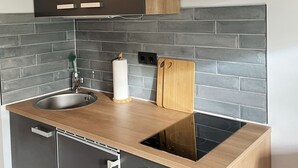 A modern kitchen with dark cabinets, a stainless steel sink, a wooden countertop, and a built-in stove. - Modern vacation apartment with terrace in Büsum (Büsum)
