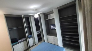 A bedroom with a bed, a ceiling fan, and a TV mounted on the wall. - Apartamento Completo Guilhermina 82 (Praia Grande)