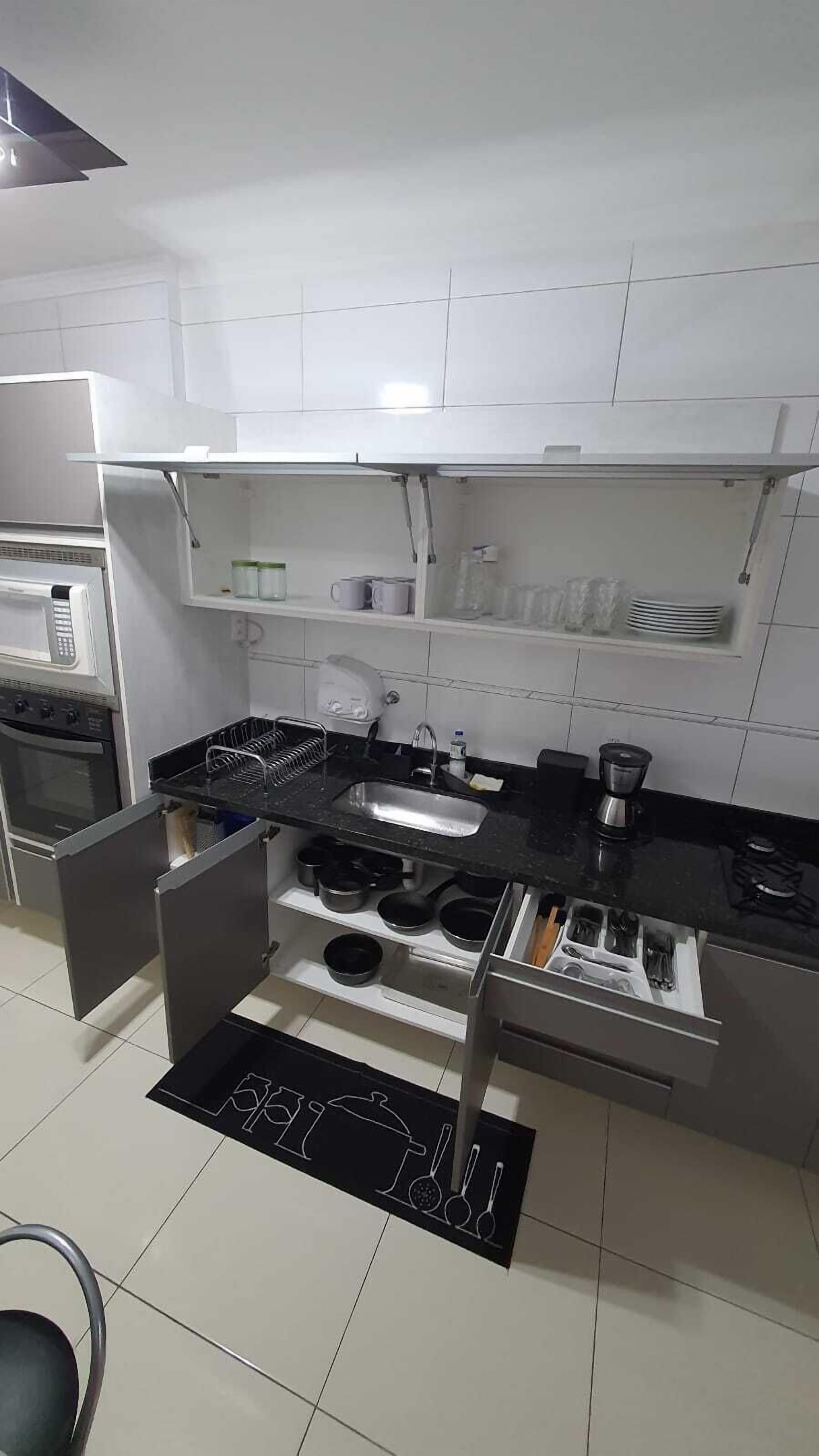 A modern kitchen with white cabinets, a black countertop, a microwave, a sink, and a coffee maker.