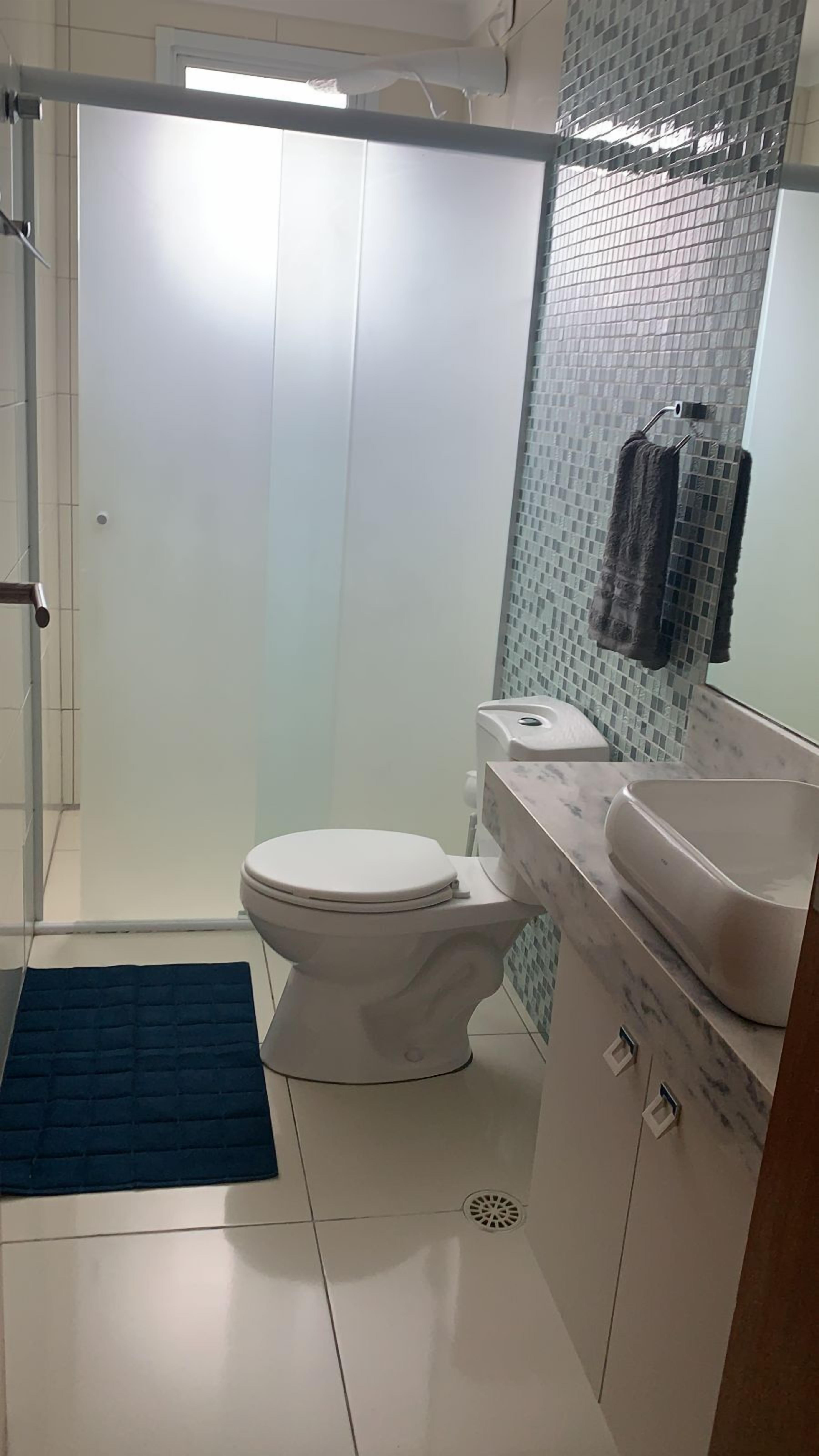 A bathroom with a white toilet, a sink, and a shower area.