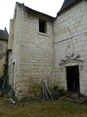 Ein Gebäude mit einer steinernen Fassade, einem kleinen Fenster und einer verzierten Tür.