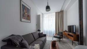 Ett modernt vardagsrum med en grå soffa, ett soffbord, ett TV-bord och en tavla på väggen.