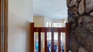 A wooden gate leading to a room with a stone wall, a window, and a view of the outside.