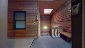 A narrow hallway with wooden walls, a bench, a fire extinguisher, and a door marked "EXIT".