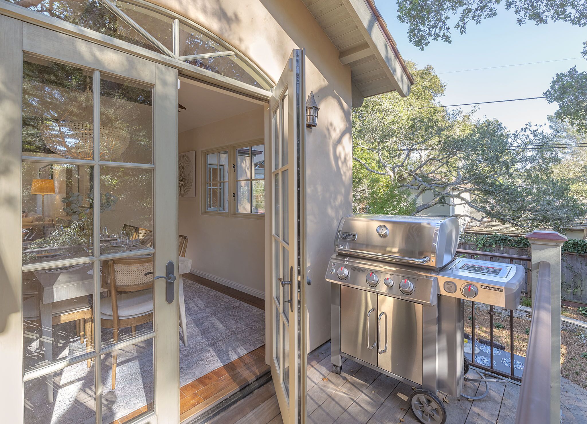 An open patio with a grill, a dining table, and chairs.