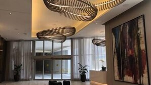 A modern hotel lobby with a large glass door entrance, a high ceiling with unique lighting fixtures, and a large abstract painting on the wall. - 2402 Hyde House Ocean View 2 Be 2 Ba, Special Amenities (Hollywood)