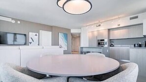A modern kitchen with white cabinets, a central island, and a dining area with a round table and chairs. - 2402 Hyde House Ocean View 2 Be 2 Ba, Special Amenities (Hollywood)