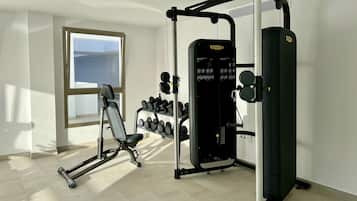 A gym with a bench press, dumbbells, and a Smith machine.
