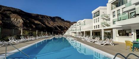A swimming pool with lounge chairs and a mountain backdrop.