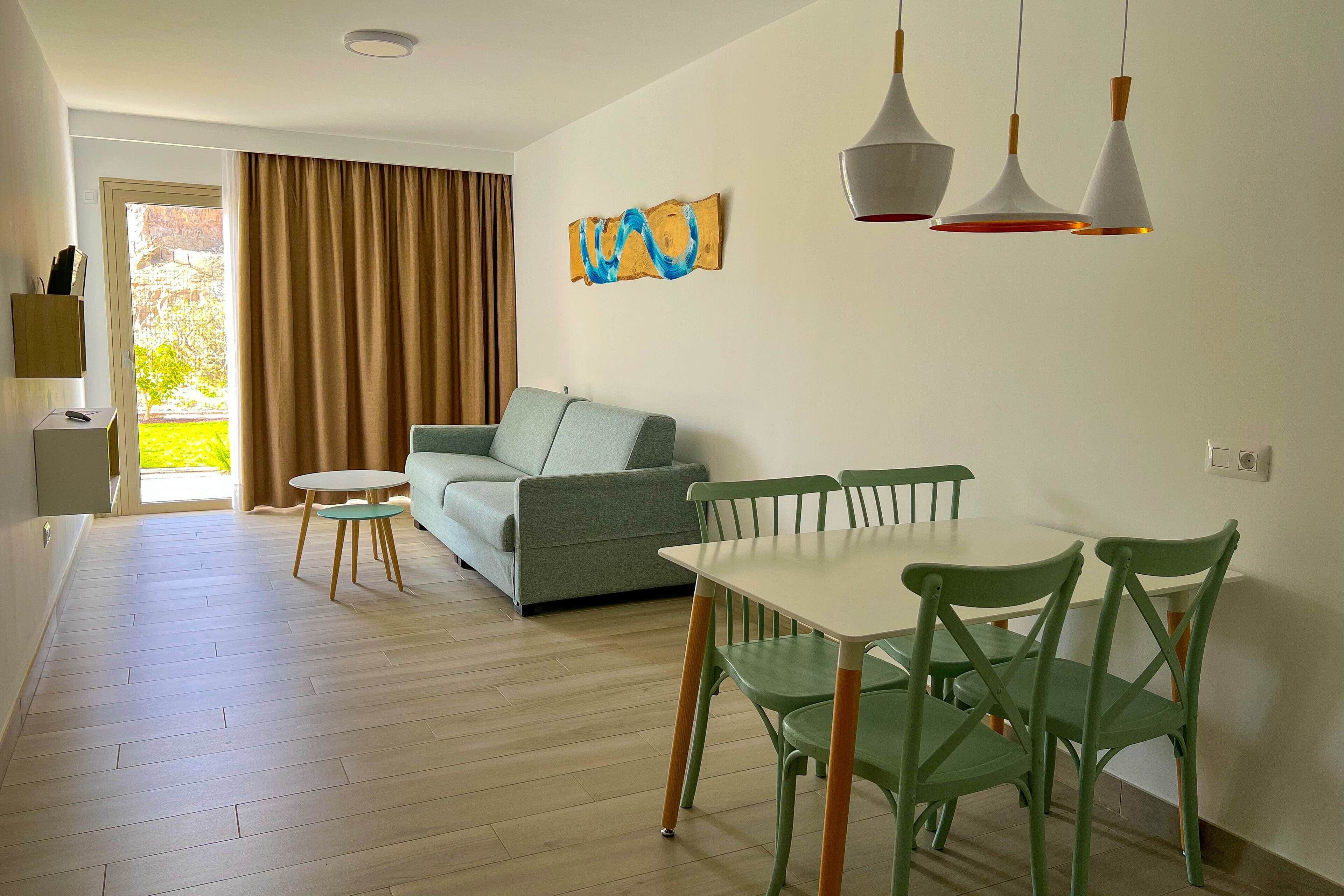 A modern living room with a sofa, a dining table with chairs, and a painting on the wall.
