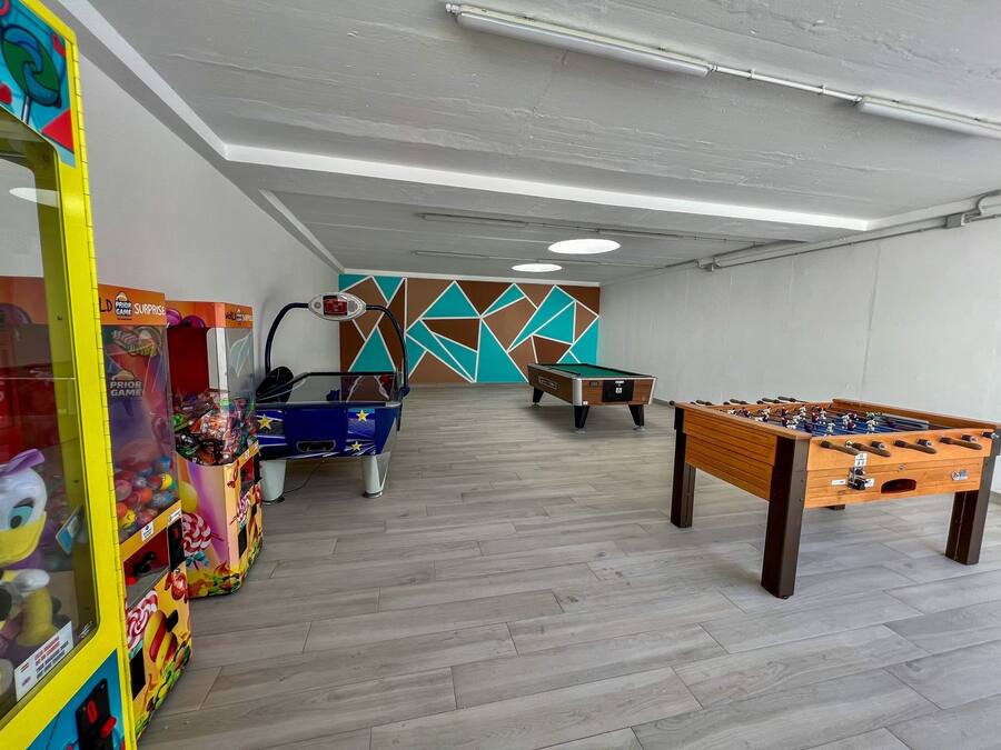 A recreational room with a pool table, foosball table, and a claw machine.