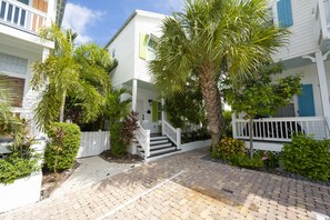 A white building with a porch, steps, and a white fence.